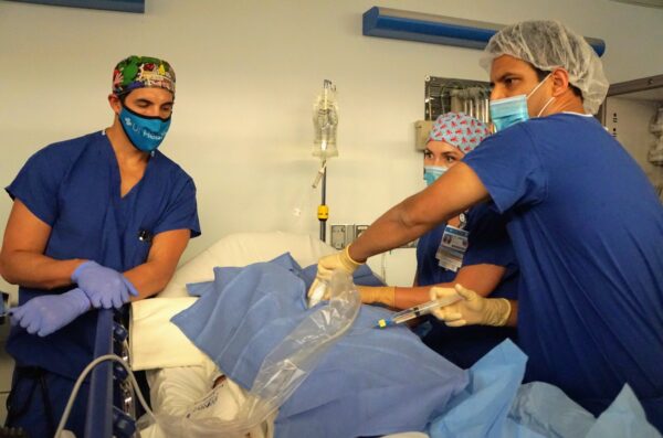 Students in scrubs work in a hospital setting
