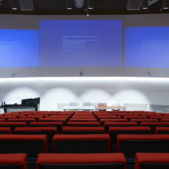 An empty auditorium with presentation slides on a big screen.