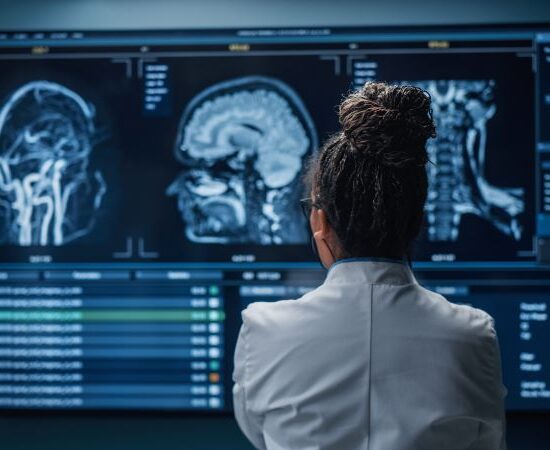 A person in a lab coat looks at brain imaging scans