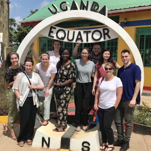 A group of students pose in front of a tourist attraction in Uganda