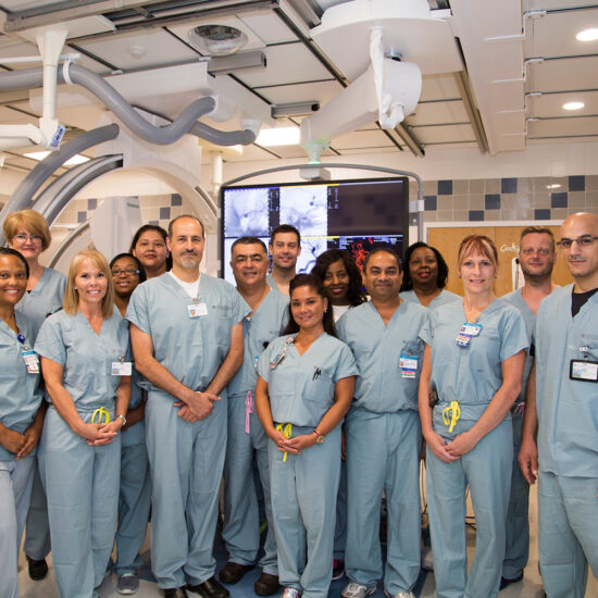 A group of doctors in scrubs pose for a group photo in a hospital environment